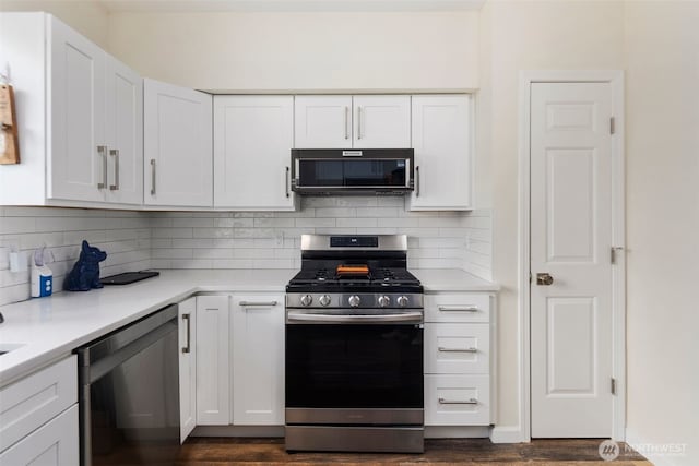 kitchen featuring stainless steel appliances, white cabinetry, dark wood-type flooring, and light countertops