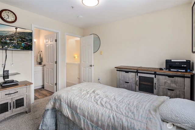 carpeted bedroom featuring wood finished floors and ensuite bathroom