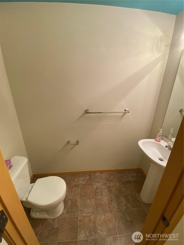 bathroom with toilet, baseboards, and a sink