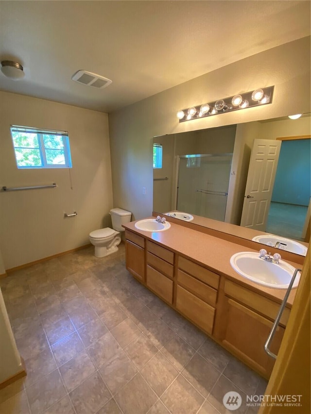 full bathroom with a stall shower, toilet, double vanity, and baseboards