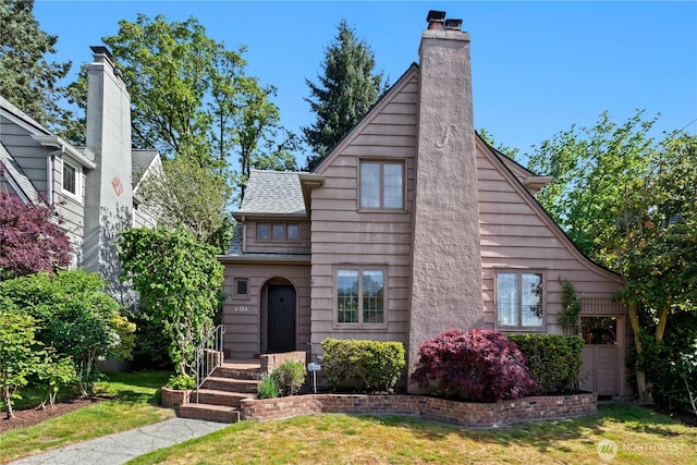 view of front of property with a front yard, a chimney, and roof with shingles