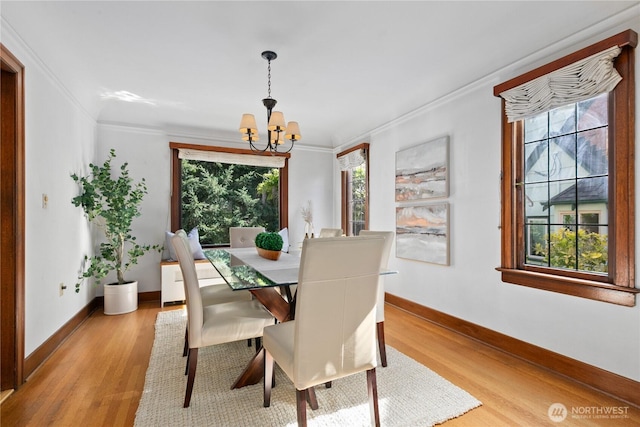 dining area with a chandelier, crown molding, light wood-type flooring, and baseboards