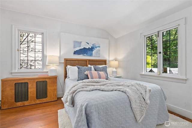 bedroom with lofted ceiling, wood finished floors, and baseboards
