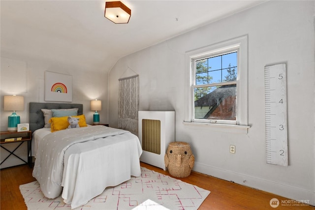 bedroom featuring wood finished floors, vaulted ceiling, and baseboards