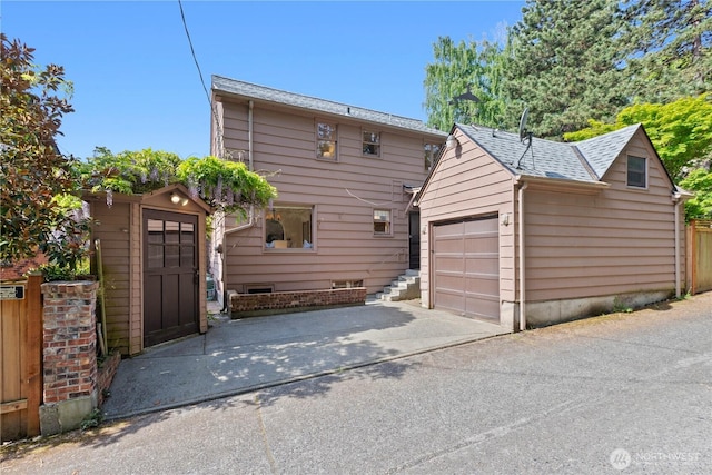 view of front of property with a garage, an outdoor structure, asphalt driveway, fence, and roof with shingles