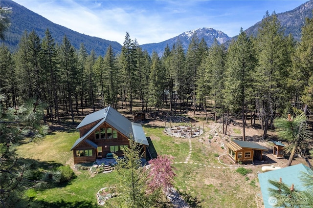 aerial view of property and surrounding area featuring mountains and a forest