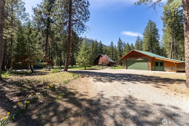 view of dirt / gravel driveway with a forest view