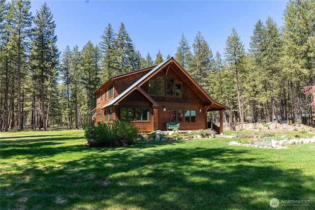 view of front facade with a front yard and a forest view