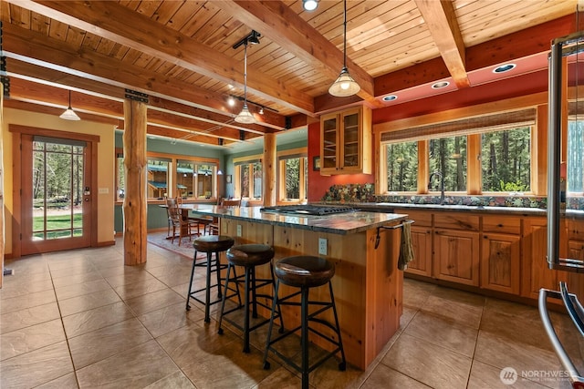 kitchen featuring wood ceiling, healthy amount of natural light, beam ceiling, a sink, and a breakfast bar area