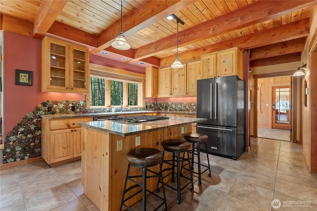 kitchen with high end refrigerator, light brown cabinetry, wooden ceiling, stainless steel gas cooktop, and beam ceiling