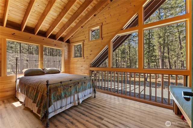 bedroom featuring wood walls, wood finished floors, beamed ceiling, multiple windows, and wood ceiling