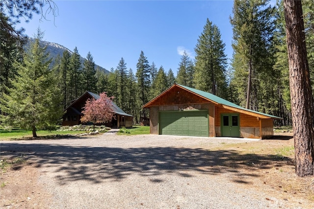 garage featuring a forest view and gravel driveway