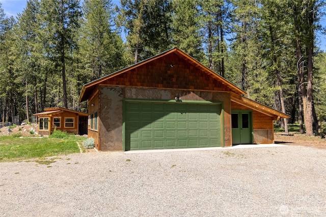 garage with driveway and a view of trees