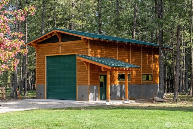 view of front of home with metal roof, an outdoor structure, a front yard, and driveway