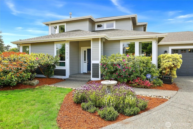 view of front of property featuring a garage, a shingled roof, and a front lawn