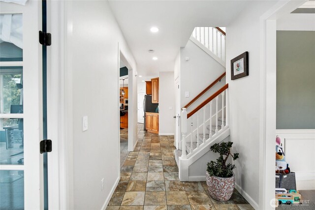 hall with stone tile flooring, stairway, baseboards, and recessed lighting