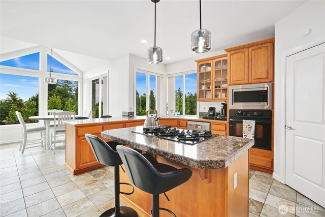 kitchen featuring appliances with stainless steel finishes, a center island, glass insert cabinets, a breakfast bar, and light tile patterned floors