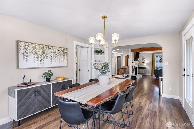 321 Park Pl, Lynden, WA 98264 - dining room featuring arched walkways, a chandelier, dark wood-style flooring, and baseboards
