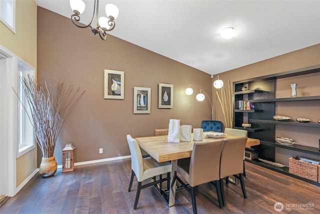 dining room with a chandelier, dark wood finished floors, baseboards, and vaulted ceiling