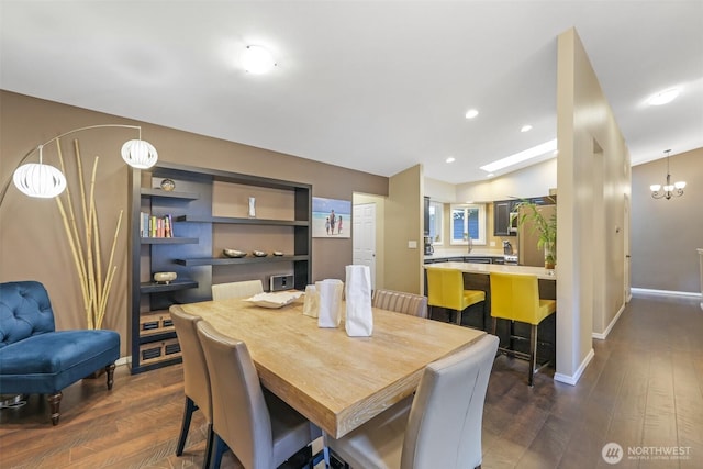dining area featuring dark wood-style flooring, baseboards, and a chandelier