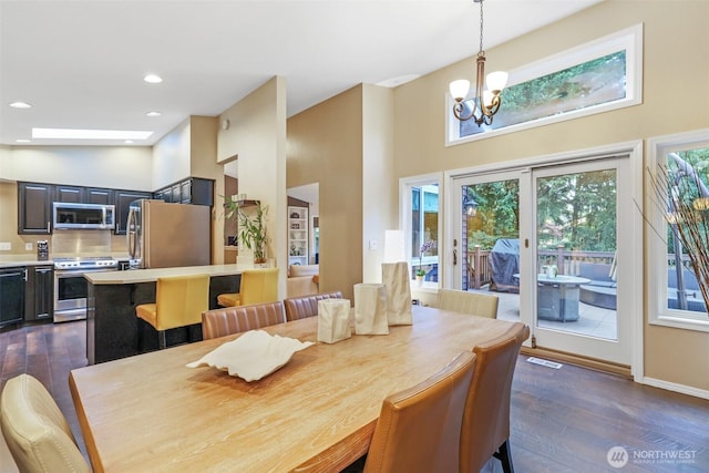 dining room with a high ceiling, dark wood-type flooring, a chandelier, recessed lighting, and baseboards