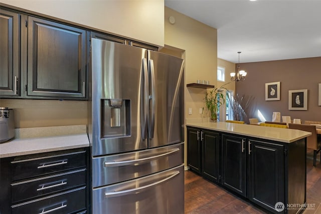 kitchen featuring stainless steel fridge with ice dispenser, dark cabinetry, light countertops, a peninsula, and dark wood-style floors
