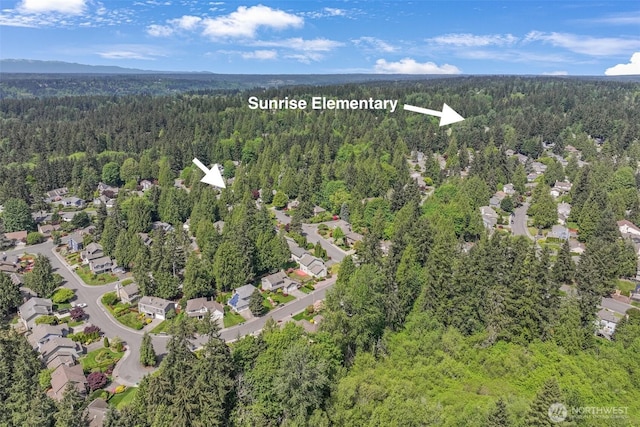 aerial view of property's location featuring a heavily wooded area and nearby suburban area