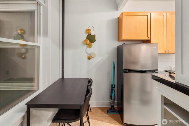 905 NE 43rd Ave Unit 110, Seattle, WA 98105 - kitchen featuring freestanding refrigerator, backsplash, baseboards, light tile patterned floors, and light brown cabinetry