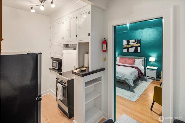 905 NE 43rd Ave Unit 110, Seattle, WA 98105 - kitchen featuring freestanding refrigerator, white cabinetry, stainless steel microwave, dark countertops, and light tile patterned floors