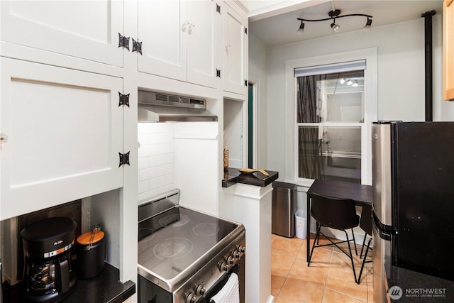 905 NE 43rd Ave Unit 110, Seattle, WA 98105 - kitchen with stainless steel appliances, under cabinet range hood, white cabinetry, and light tile patterned floors