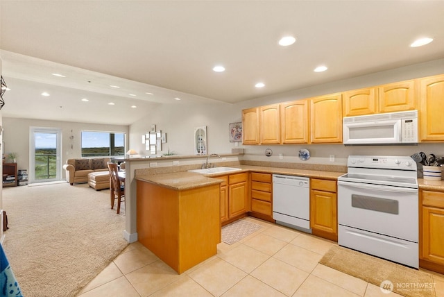 kitchen with white appliances, a sink, recessed lighting, a peninsula, and light countertops