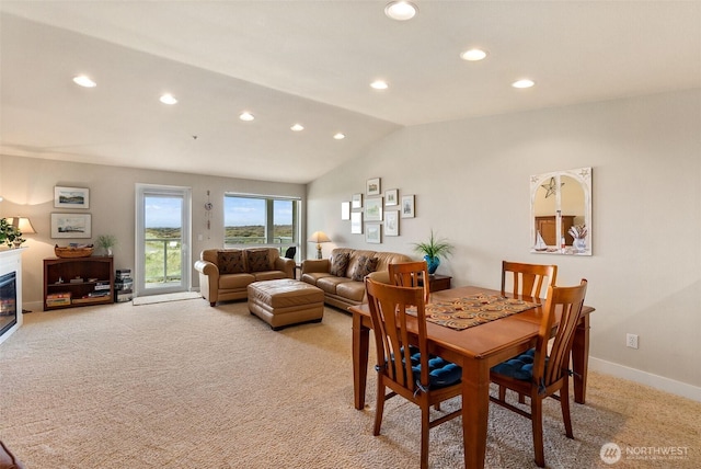 dining room featuring light carpet, vaulted ceiling, recessed lighting, a glass covered fireplace, and baseboards