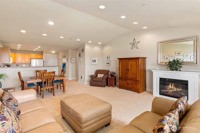 living room with recessed lighting, light carpet, vaulted ceiling, baseboards, and a glass covered fireplace