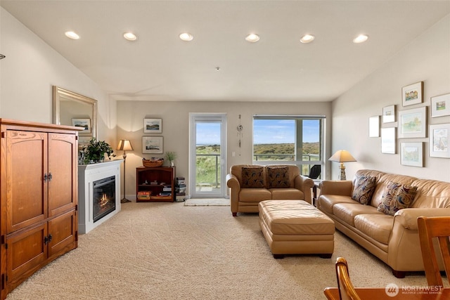 living room with light carpet, recessed lighting, and a glass covered fireplace