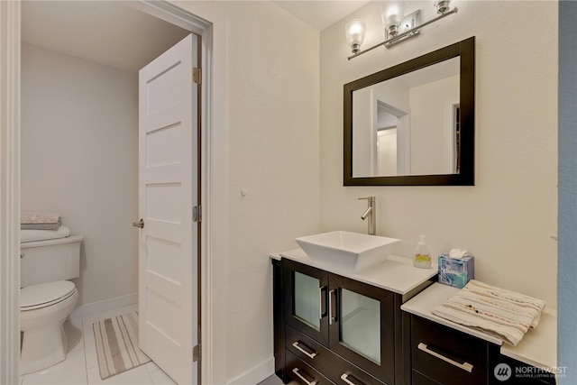 bathroom featuring toilet, tile patterned floors, vanity, and baseboards