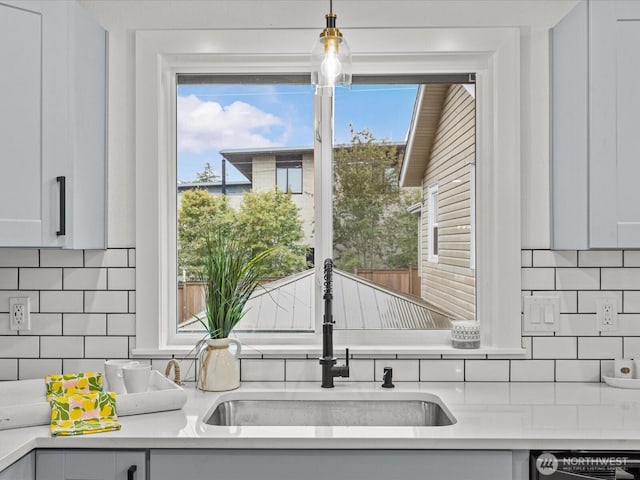 kitchen with a sink, black dishwasher, light countertops, and backsplash