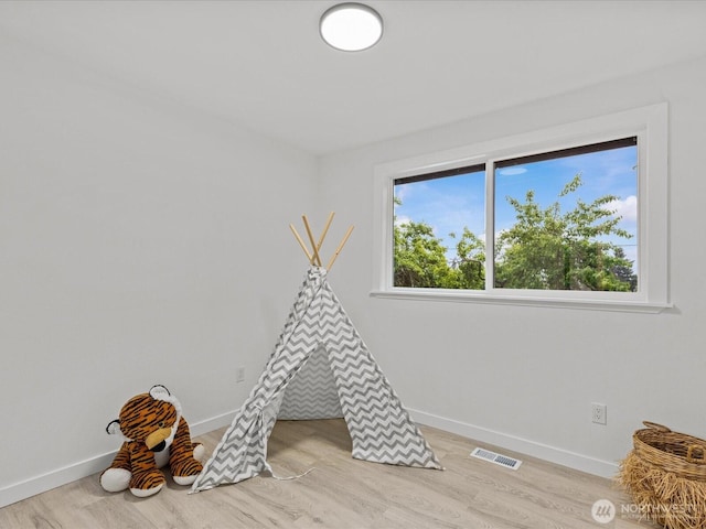 recreation room with baseboards and light wood-style flooring