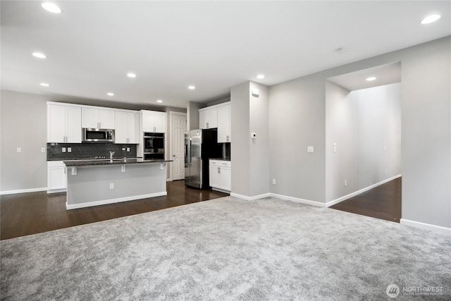 4933 Wanderlust Way, Gig Harbor, WA 98332 - kitchen with stainless steel appliances, dark countertops, dark colored carpet, a center island with sink, and recessed lighting