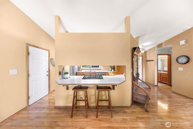 8224 Quinault Rd, Blaine, WA 98230 - kitchen featuring lofted ceiling, light wood-style flooring, a sink, stainless steel gas stovetop, and a breakfast bar