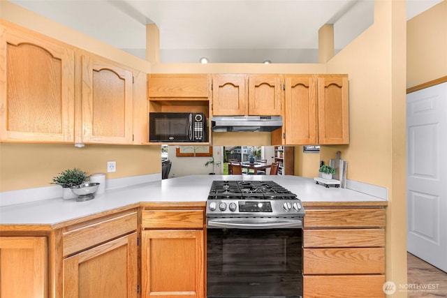 8224 Quinault Rd, Blaine, WA 98230 - kitchen featuring stainless steel range with gas cooktop, black microwave, under cabinet range hood, light countertops, and a peninsula