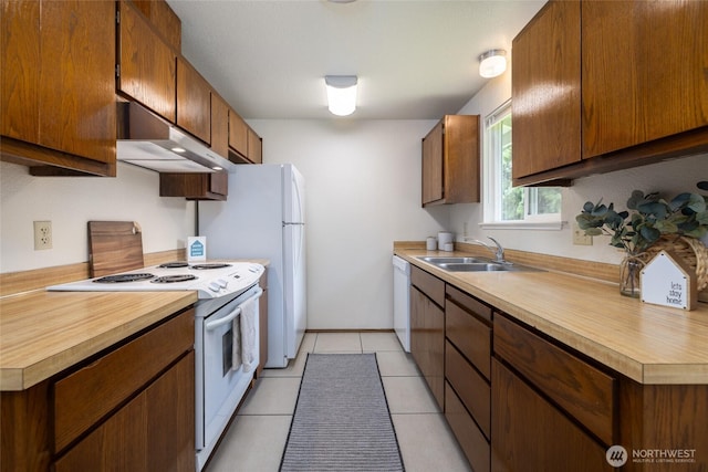 kitchen featuring white appliances, a sink, under cabinet range hood, light countertops, and light tile patterned floors