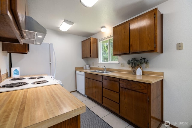 kitchen featuring white appliances, light countertops, a sink, range hood, and light tile patterned floors