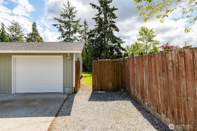 garage with fence and concrete driveway