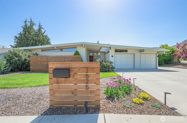 view of front facade with concrete driveway, an attached garage, and fence