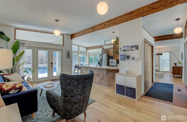 living room featuring beam ceiling, french doors, light wood-type flooring, plenty of natural light, and a textured ceiling