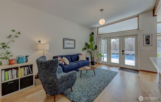 living area with french doors, wood finished floors, a textured ceiling, and baseboards