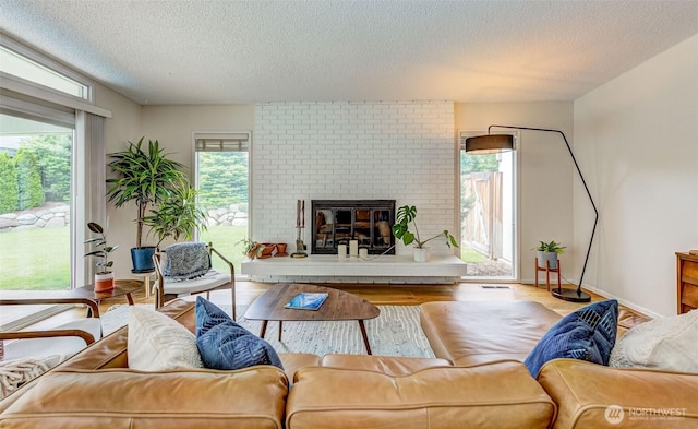 living area featuring a textured ceiling, healthy amount of natural light, wood finished floors, and a fireplace