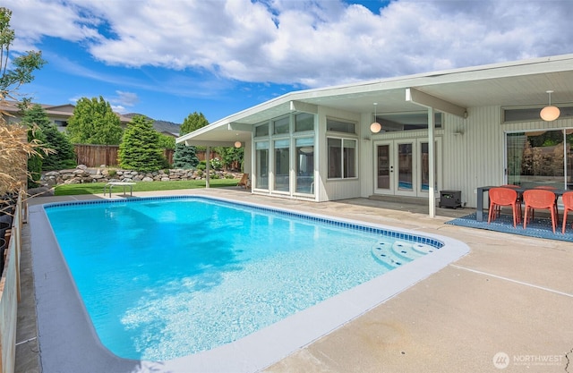 view of pool with french doors, a patio area, fence, a sunroom, and a diving board