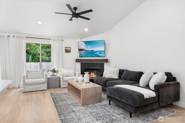 living area with vaulted ceiling, a tile fireplace, ceiling fan, light wood-style flooring, and recessed lighting
