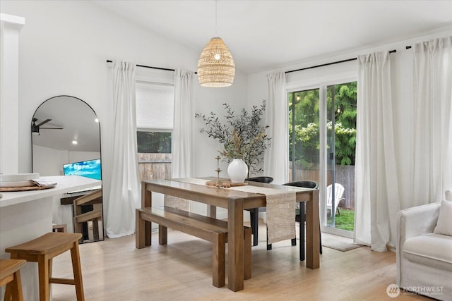 dining room with light wood-style flooring and vaulted ceiling